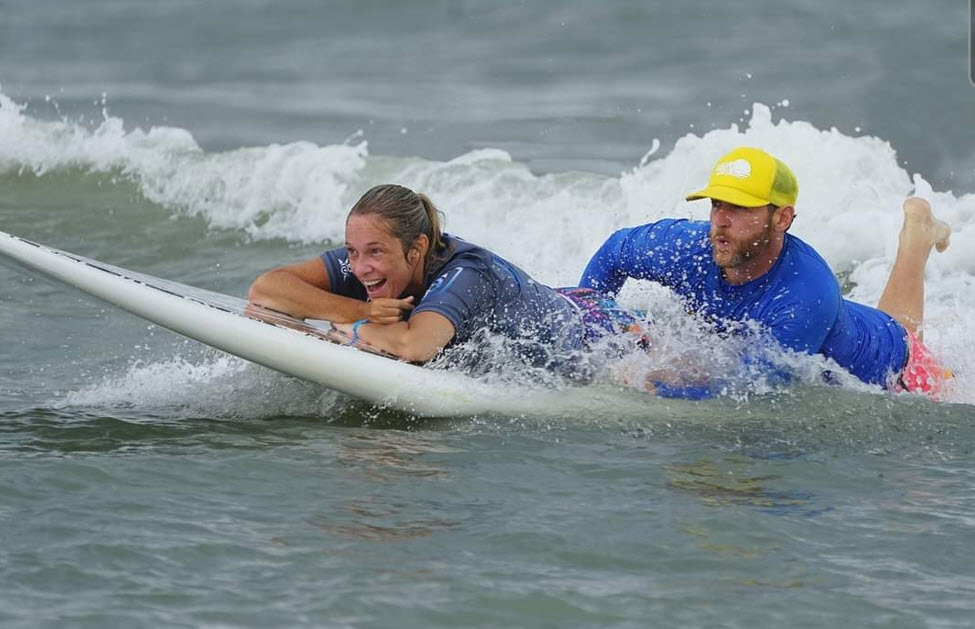 Ali on surfboard with surfing partner in ocean